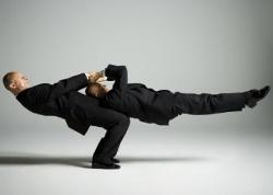 Profile of two male acrobats in business suits performing